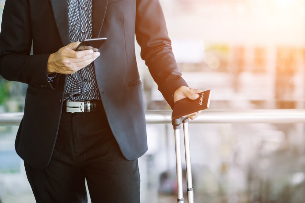 Mann mit Smartphone am Flughafen